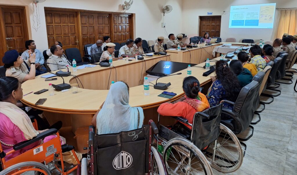 This image shows a group of police men and and group of women in wheelchairs, sitting around a table and focusing on ppt in front of them.