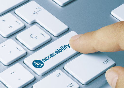 A close-up shot of a keyboard with a person's finger pressing the 'accessibility' key, which features a wheelchair symbol and the word "accessibility" in blue.