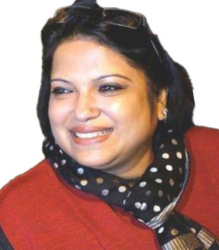 Dr. Anjlee Agarwal is wearing a red top and a black scarf with white polka dots around her neck.