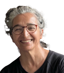 Anju Pandey, a woman with white hair wearing a black t shirt and specs is smiling towards the camera.