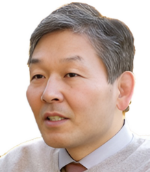 Dr. Yoshihiko Kawauchi, is wearing a grey shirt and a brown sweater with a neat hairstyle.