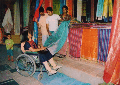 A lady in wheelchair choosing clothes in a shop